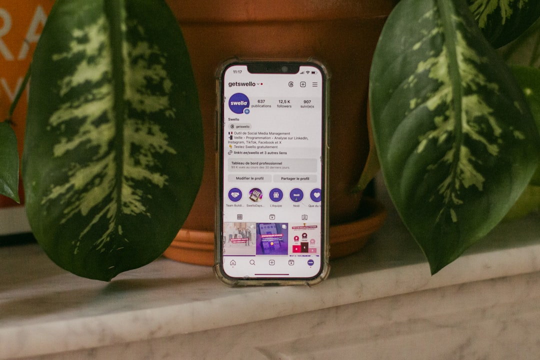 A cell phone sitting on top of a counter next to a potted plant