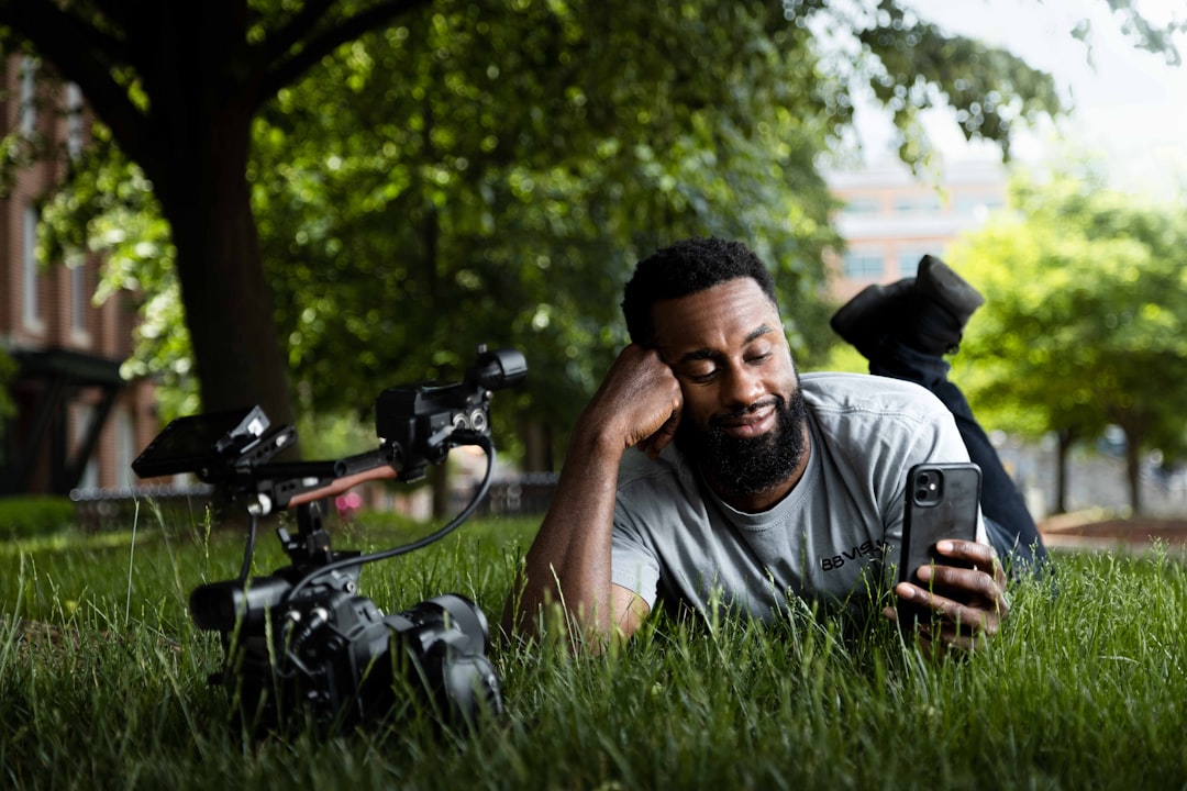a man laying in the grass next to a camera
