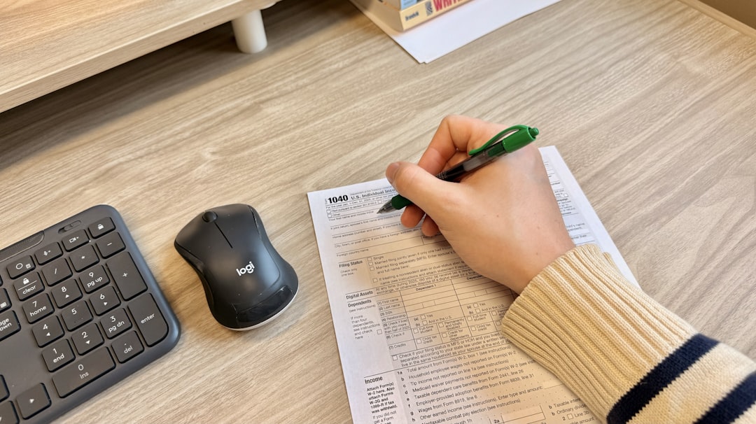Hand writing on document next to keyboard and mouse.