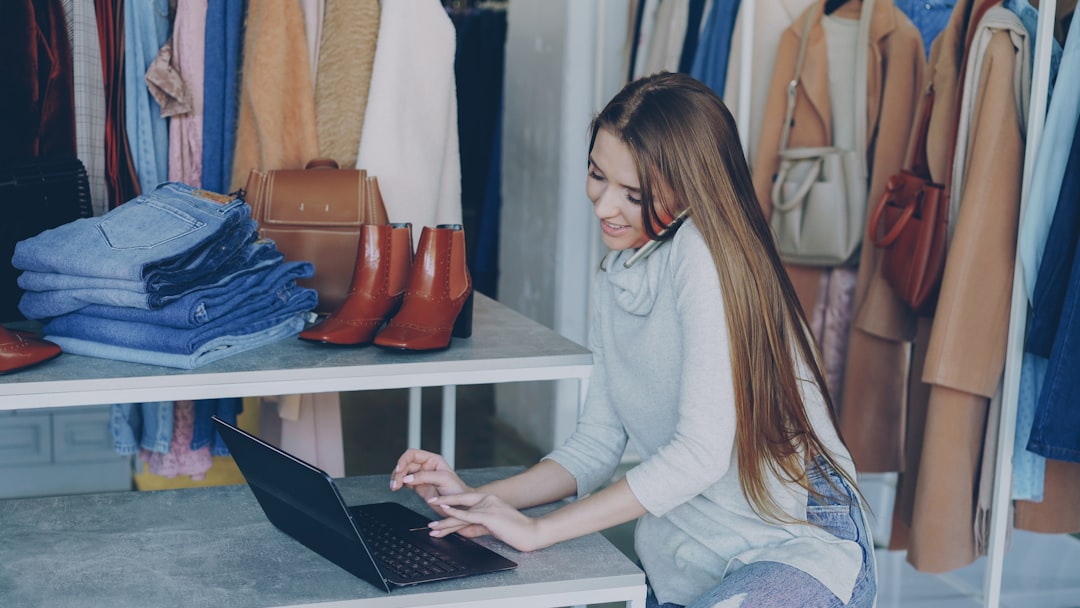 Woman working on a laptop surrounded by clothes